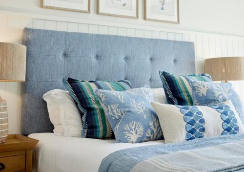 a bed with blue and white pillows on it at St Brides Spa Hotel & Village Apartments in Saundersfoot
