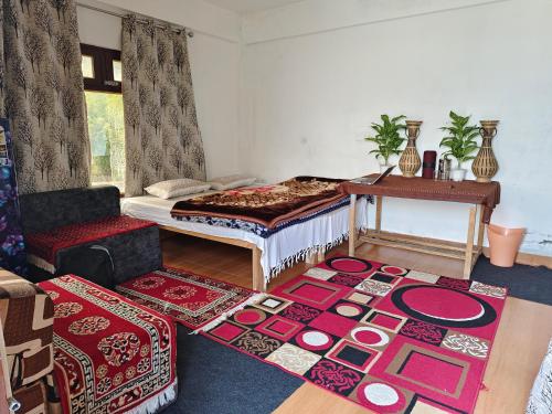a room with a bed and a table and some rugs at Nanda rawat Homestay in Munsyari