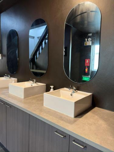 two sinks in a bathroom with two mirrors at Hood hostel in Jomtien Beach