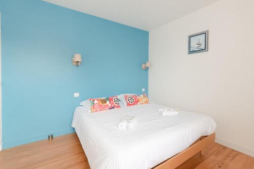 une chambre avec un lit blanc avec un mur bleu dans l'établissement LA LIBELLULE - 5prsProche de Pornichet, à Pornichet
