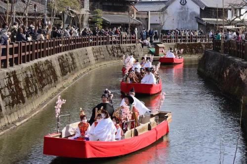 a group of people riding in red boats on a river at 顔house 若水庵 築100年の古民家ステイ 北総の田園に佇む和の隠れ家 最大12名宿泊可 in Katori