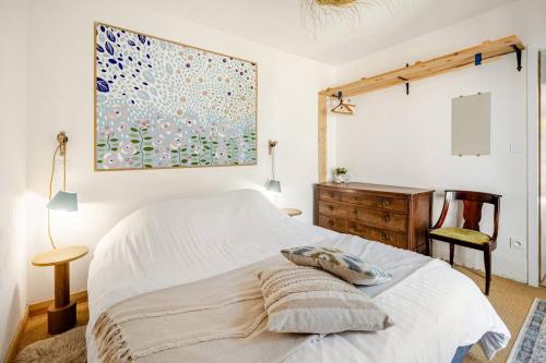 a bedroom with a bed and a desk and a painting at Le petit logis in La Châtaigneraie