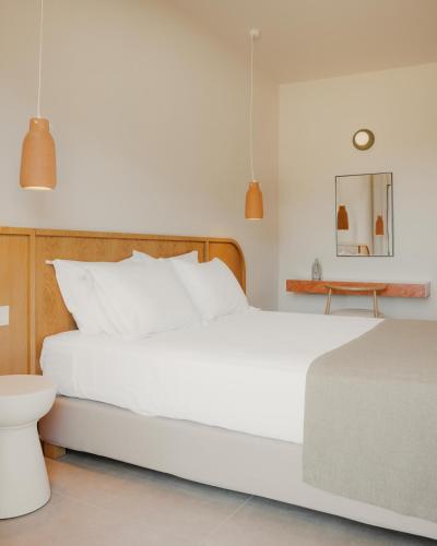 a bedroom with a large white bed and a table at Hotel Apollon Corfu in Paleokastritsa