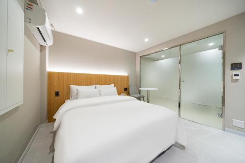 a bedroom with a white bed and a glass shower at Cream Hotel in Guri