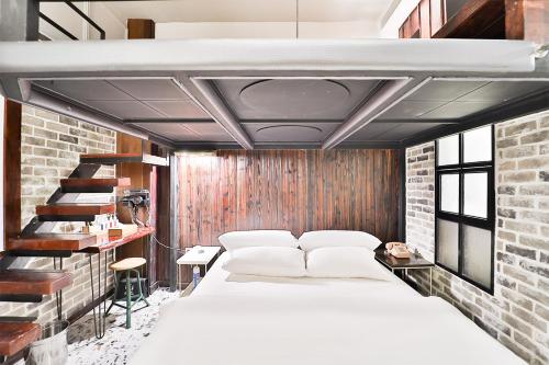 a bedroom with a white bed and a brick wall at Daegu February Hotel Hwanggeum in Daegu