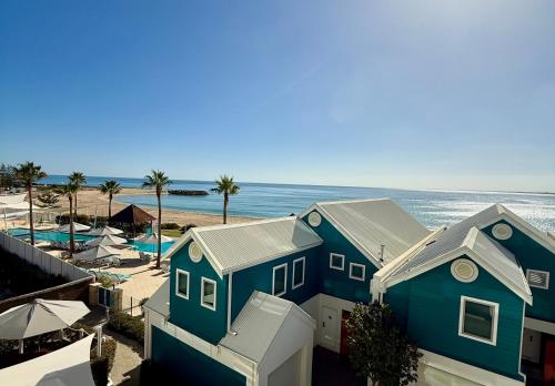 a blue house next to a beach with the ocean at TEMPEL by the Sea in Mandurah