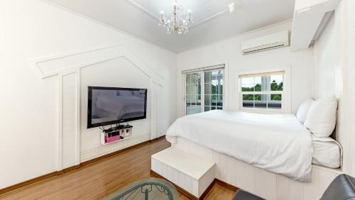 a white bedroom with a bed and a tv at Gapyeong ID pension in Gapyeong