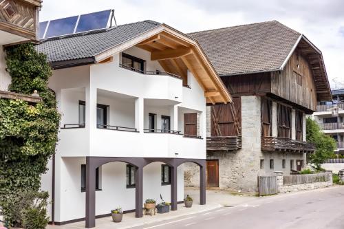 a house with a gambrel roof and white facade at Krämerhof Apt Villnösser Geisler in Rodengo
