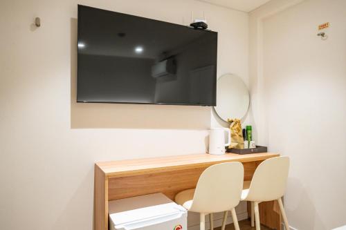 a room with a television on the wall with two chairs at Cream Hotel in Guri