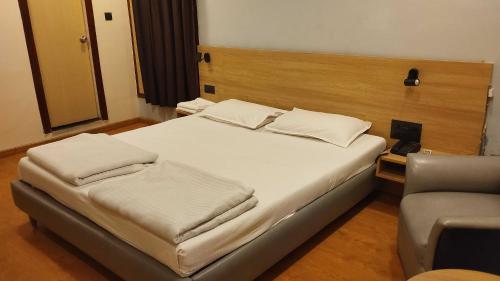 a bedroom with a bed and a chair at Townhouse Naksalbari Railway Station in Siliguri