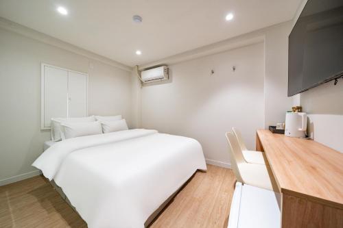 a bedroom with a large white bed and a kitchen at Cream Hotel in Guri