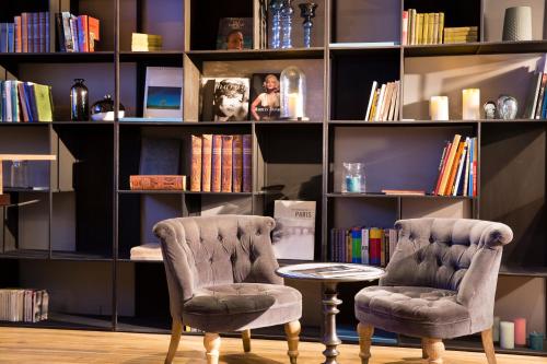 two chairs and a table in front of a book shelf at Hotel Mademoiselle in Paris