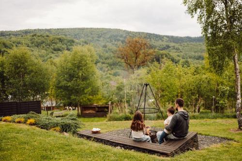 a family sitting on a wooden board in a garden at CzillChata - dom z balią in Maków Podhalański