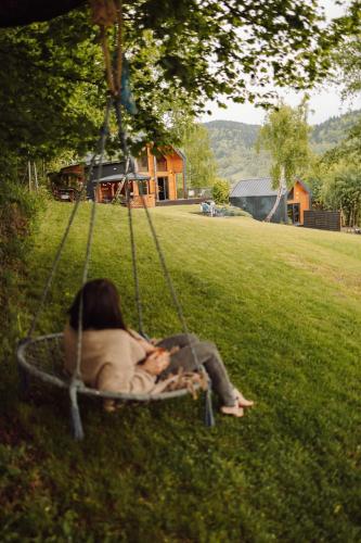 a woman sitting in a swing in the grass at CzillChata - dom z balią in Maków Podhalański