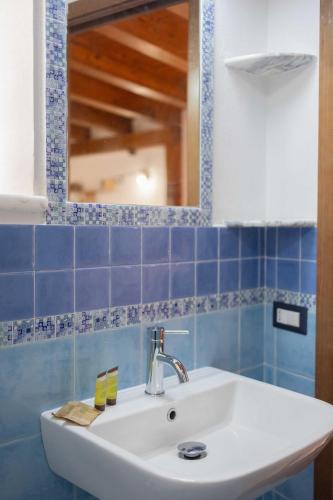a bathroom sink with a mirror and blue tiles at Dalì alla rocca in Cefalù