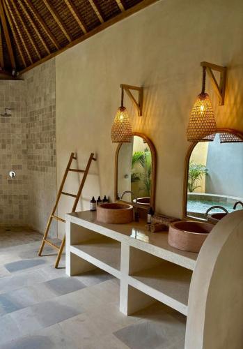 a bathroom with two sinks and two mirrors at Villa Keluarga in Gili Air