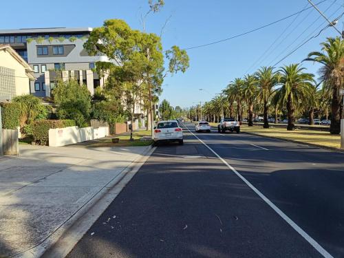 a street with cars driving down a street with palm trees at Cute, Cozy and Central Apt 2 in Melbourne