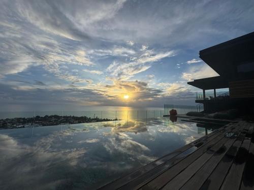 a pool of water with the sun in the sky at Legend Hill Resort and Spa in Rivière Noire