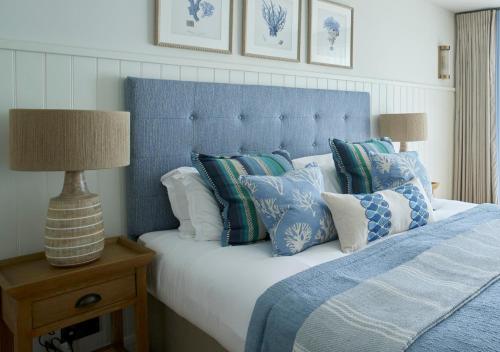 a bedroom with a bed with a blue headboard and pillows at St Brides Spa Hotel & Village Apartments in Saundersfoot