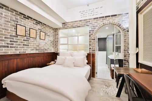 a bedroom with two beds and a brick wall at Daegu February Hotel Hwanggeum in Daegu