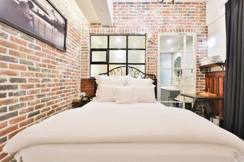 a bedroom with a white bed in a brick wall at Daegu February Hotel Hwanggeum in Daegu