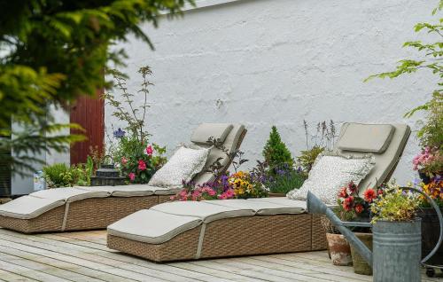 UlfborgにあるBeautiful Home In Ulfborg With Wifiの花が飾られたデッキに置かれた2つの籐のベッド