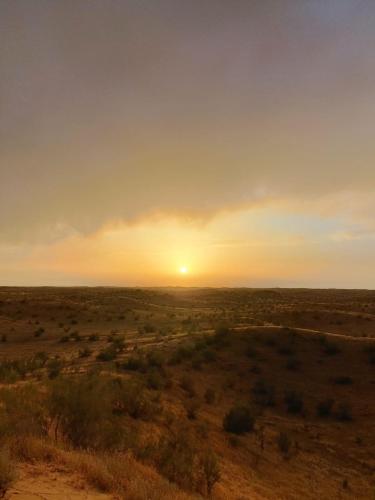 a sunset in the desert with the sun setting at Kyzylkum Nights Camp & Family Yurt in Nurota
