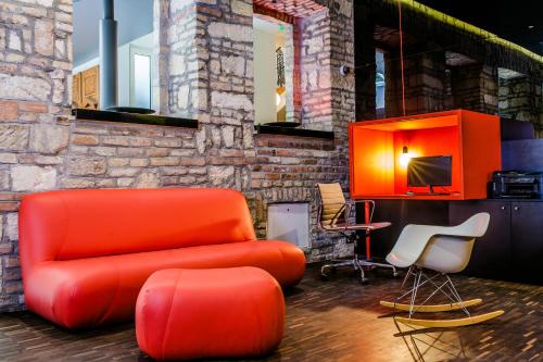 a living room with an orange couch and chairs at Casati Hotel - Adults Only in Budapest