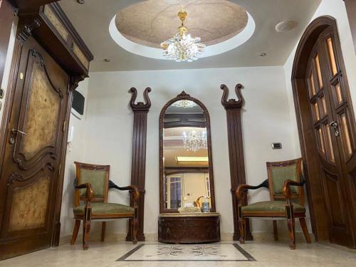 une pièce avec deux chaises, un miroir et un lustre dans l'établissement New Cairo Home, au Caire