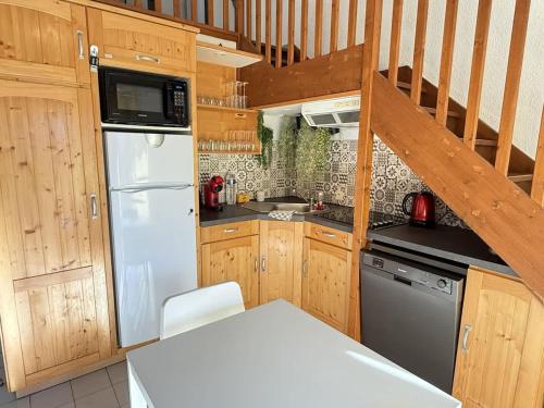 une cuisine avec des armoires en bois et un réfrigérateur blanc dans l'établissement Valras-Loc - Maison avec terrasse, parking, à Valras-Plage