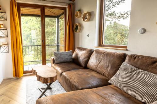 a brown leather couch in a living room with a window at Búda 2 in Komjatná