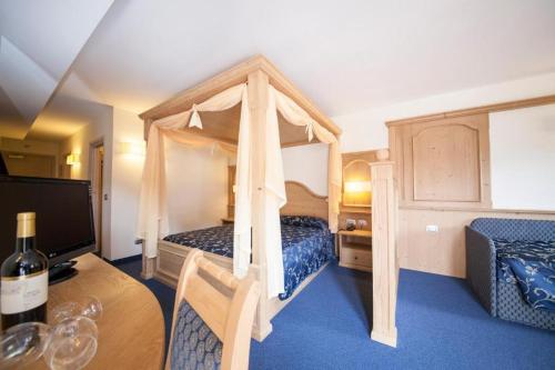 a bedroom with a canopy bed and a table with a bottle of wine at Family Hotel Andes - Only for Family in Vigo di Fassa