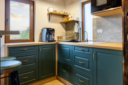 a kitchen with green cabinets and a window at Búda 2 in Komjatná