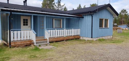 una casa blu con portico e recinzione bianca di Rauhan pesä a Karigasniemi