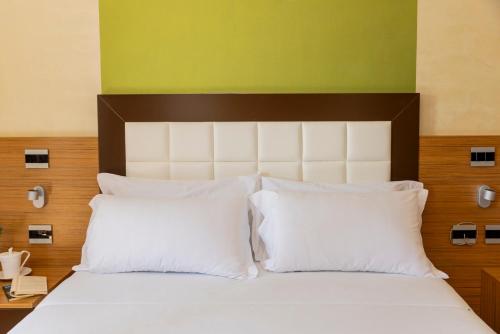 a bed with white pillows and a green wall at Hotel Monte Campo in Capracotta