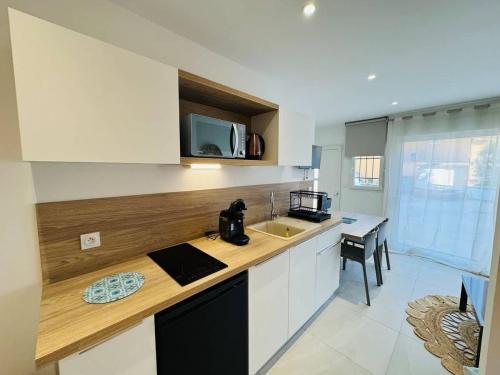 une cuisine avec des armoires blanches et un comptoir dans l'établissement Valras-Loc - Studio Moderne avec Jardin, à Valras-Plage