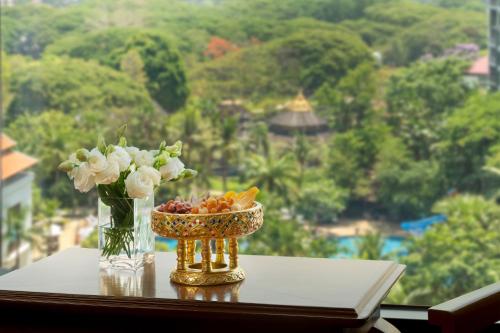 a vase of flowers and a bowl of fruit on a table at Shangri-La Chiang Mai in Chiang Mai
