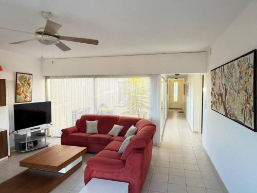 un salon avec un canapé rouge et une télévision dans l'établissement Valras-Loc - Villa sur la plage, à Valras-Plage