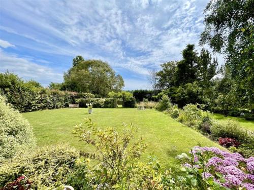 a garden with green grass and flowers and trees at Home from home in Hastings