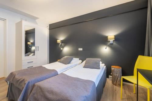 a hotel room with two beds and a yellow chair at Kuukkeli Saariselkä Inn in Saariselka