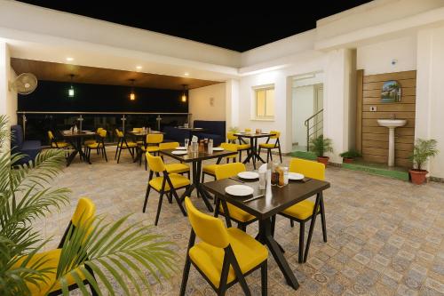 a dining room with tables and yellow chairs at Hotel The Heights in Haridwār
