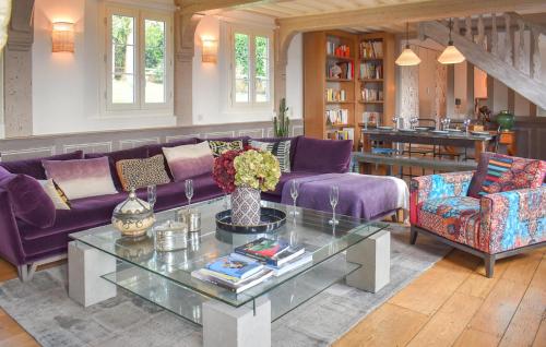 - un salon avec des canapés violets et une table en verre dans l'établissement Chaumière Normande, à Le Breuil-en-Auge