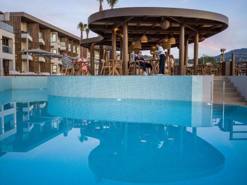 a pool at a hotel with people sitting at tables at Nalu Resort & SPA Adults Only Hotel in Adelianos Kampos