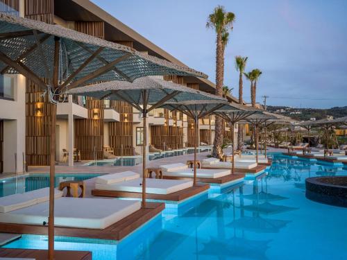 a hotel pool with chairs and umbrellas at Nalu Resort & SPA Adults Only Hotel in Adelianos Kampos