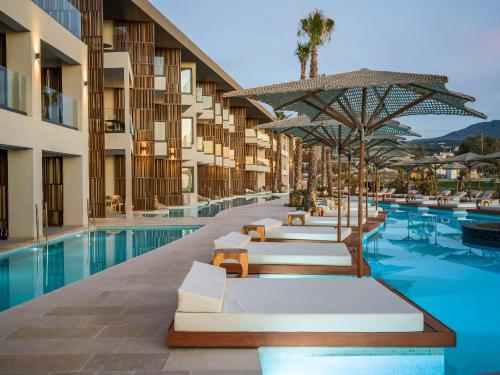 a hotel swimming pool with chairs and umbrellas at Nalu Resort & SPA Adults Only Hotel in Adelianos Kampos