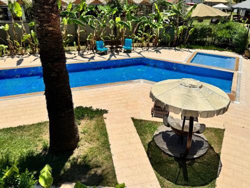 un tavolo con ombrellone accanto alla piscina di Sunyear Guest Houses 2 a Urla