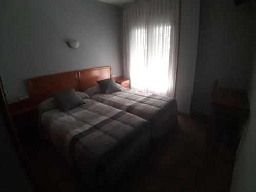 a bedroom with a bed and a window with the sunlight at Hotel Los Leones, el más cercano a Warner in San Martín de la Vega