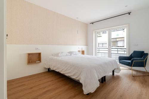 a bedroom with a bed and a blue chair at Apartamento Villa Paioryna II in Vila Verde