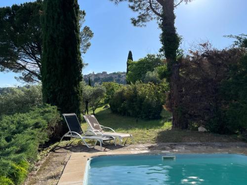une piscine avec deux chaises et un ordinateur portable dans un jardin dans l'établissement Villa La Familliale, piscine avec vue imprenable sur Gordes, à Gordes