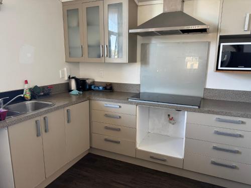 a kitchen with white cabinets and a sink at Holiday at Mount Maunganui in Mount Maunganui